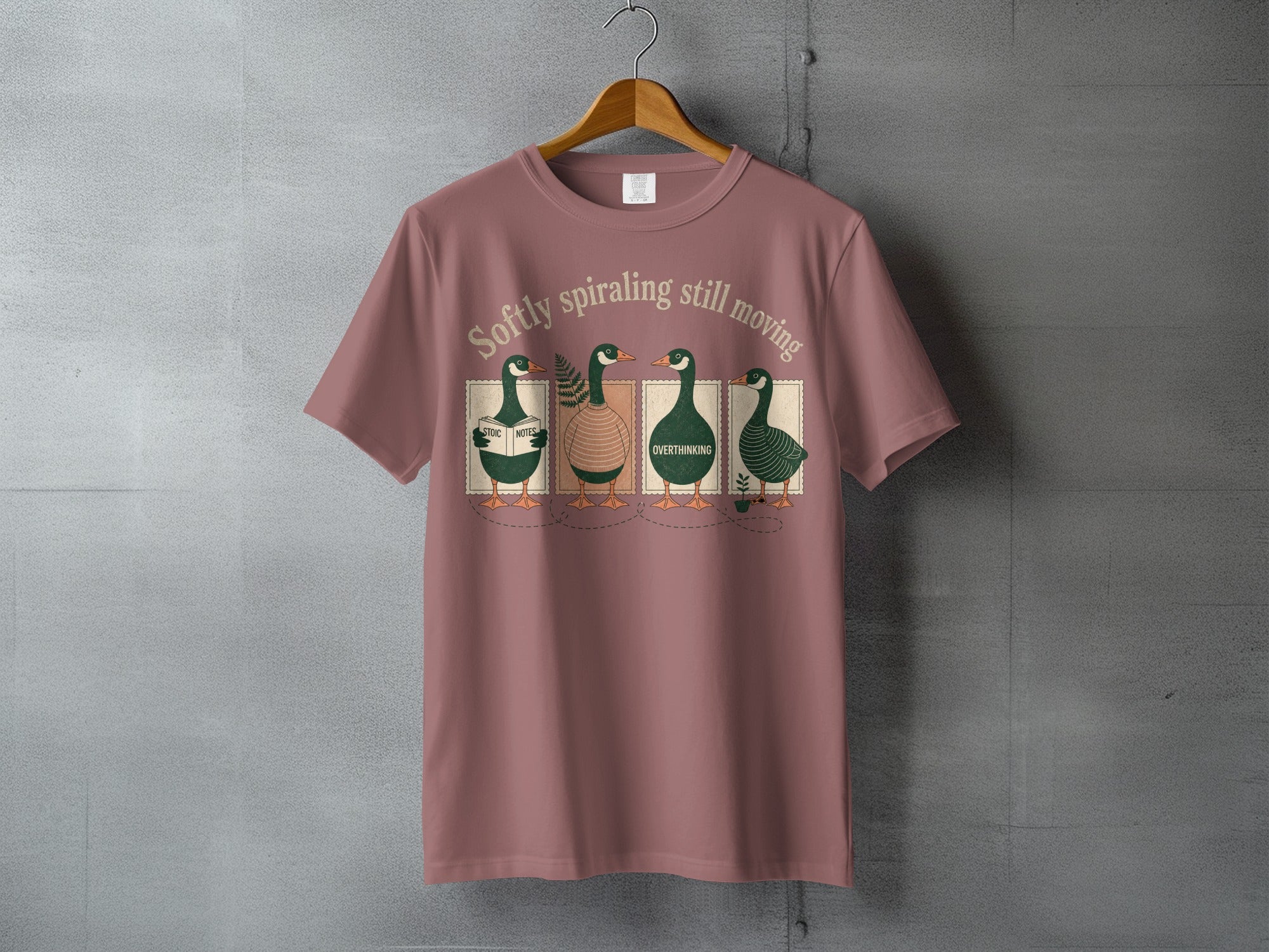 T-shirt featuring four ducks in sweaters with the text "Softly spiraling still moving".
