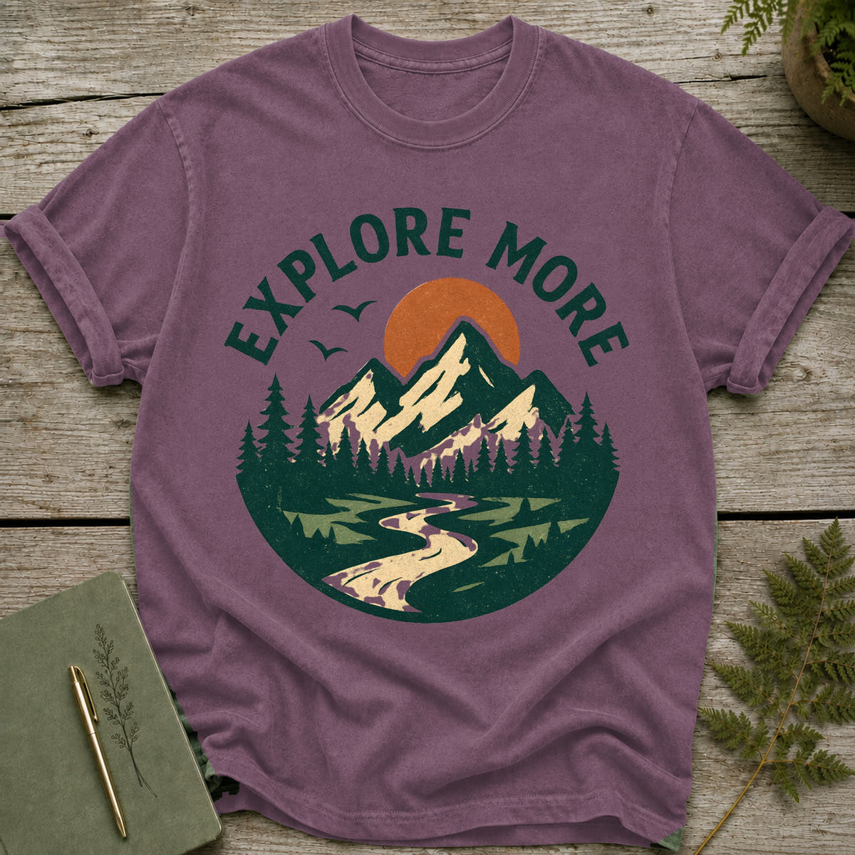 Purple t-shirt with "EXPLORE MORE" text and mountain landscape graphic.