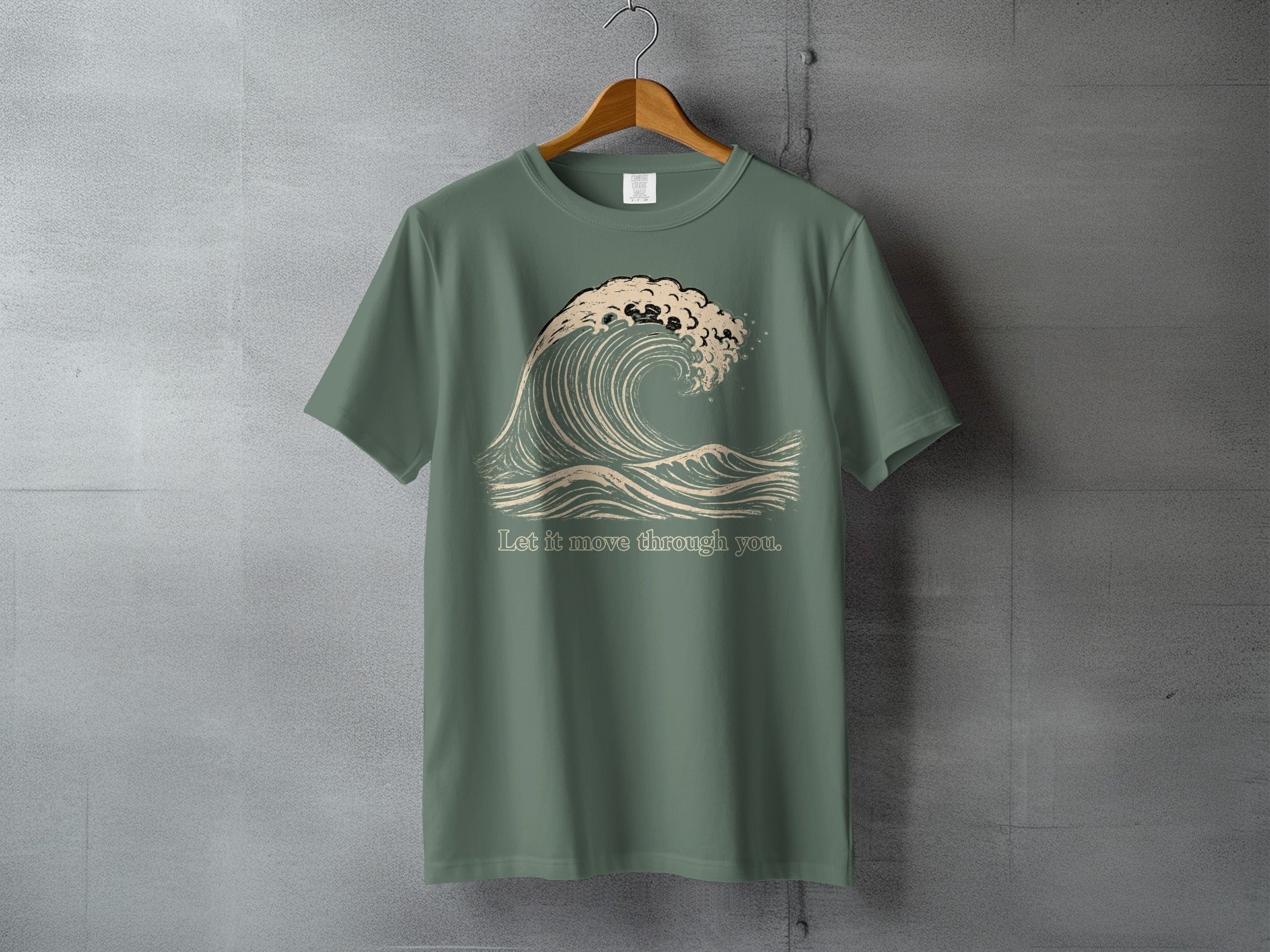 Green t-shirt with a stylized wave graphic and text "Let it move through you."