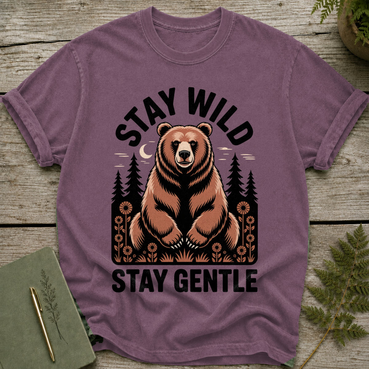 T-shirt with a graphic of a bear, trees, and moon with text "STAY WILD STAY GENTLE".