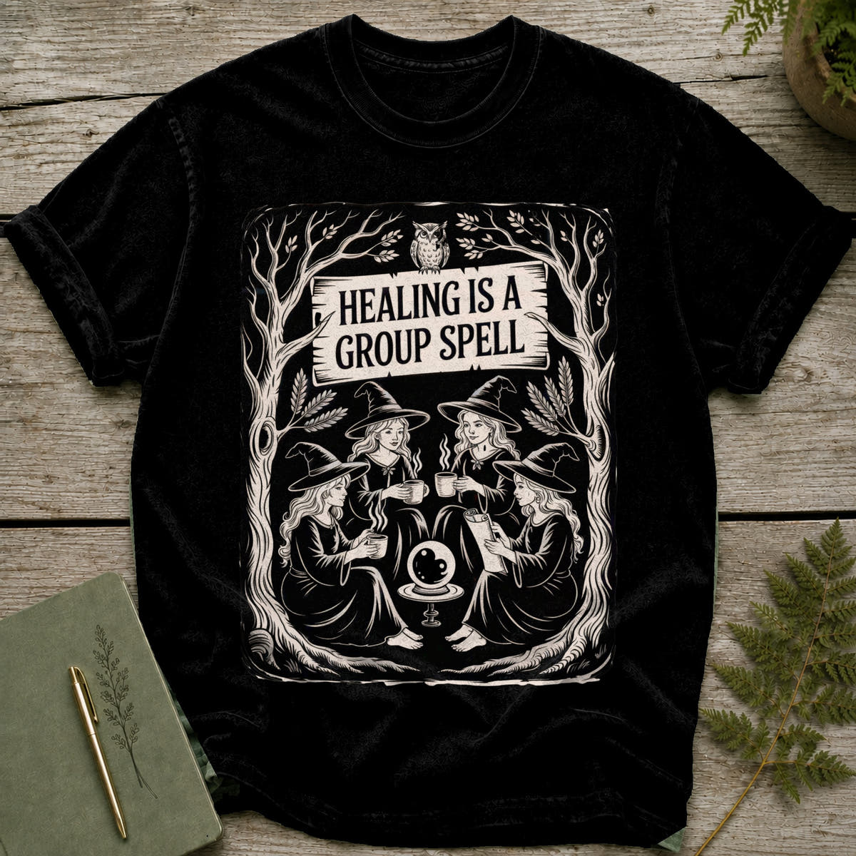 Black t-shirt with "HEALING IS A GROUP SPELL" and witches around a crystal ball.