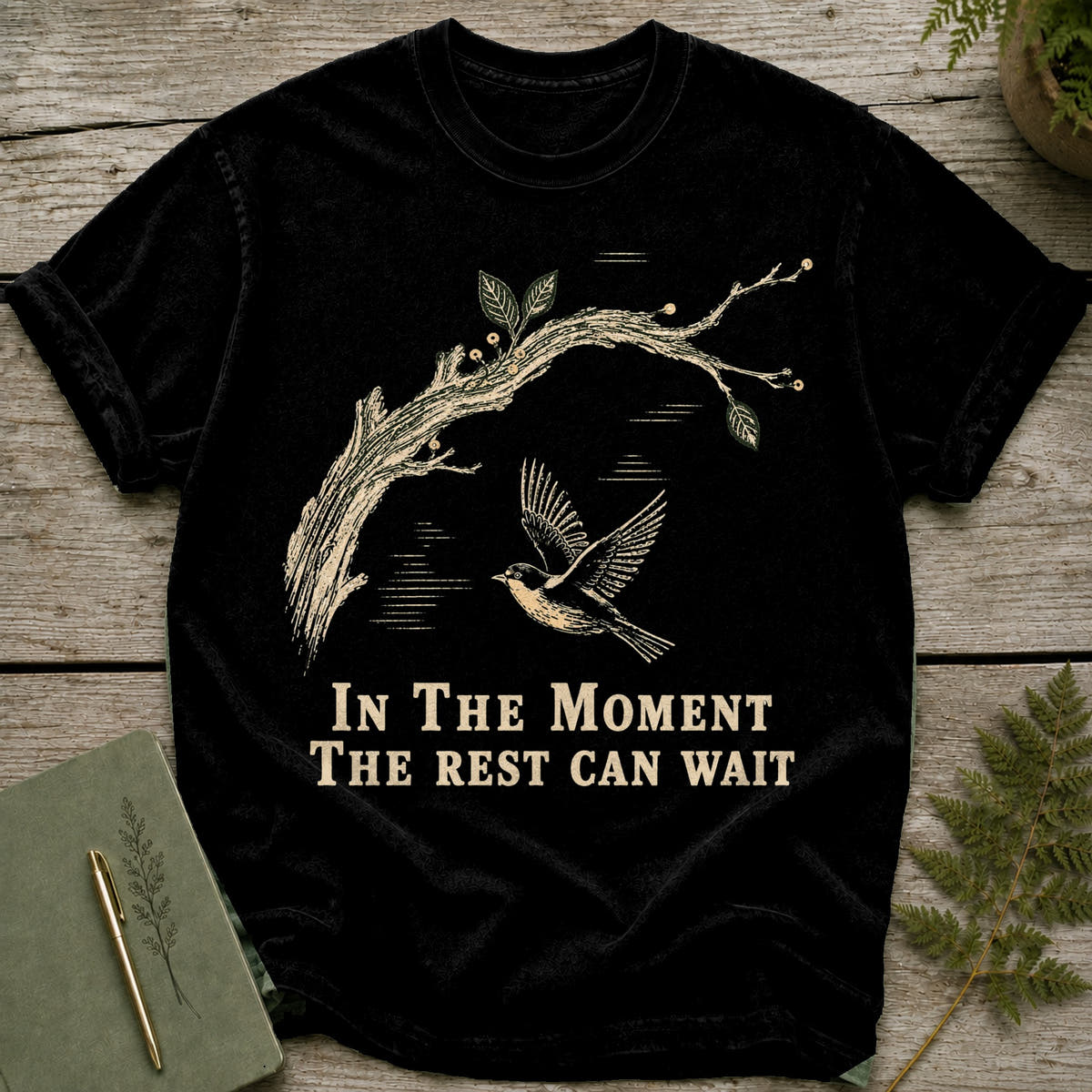Black t-shirt with a bird flying by a branch graphic and text.