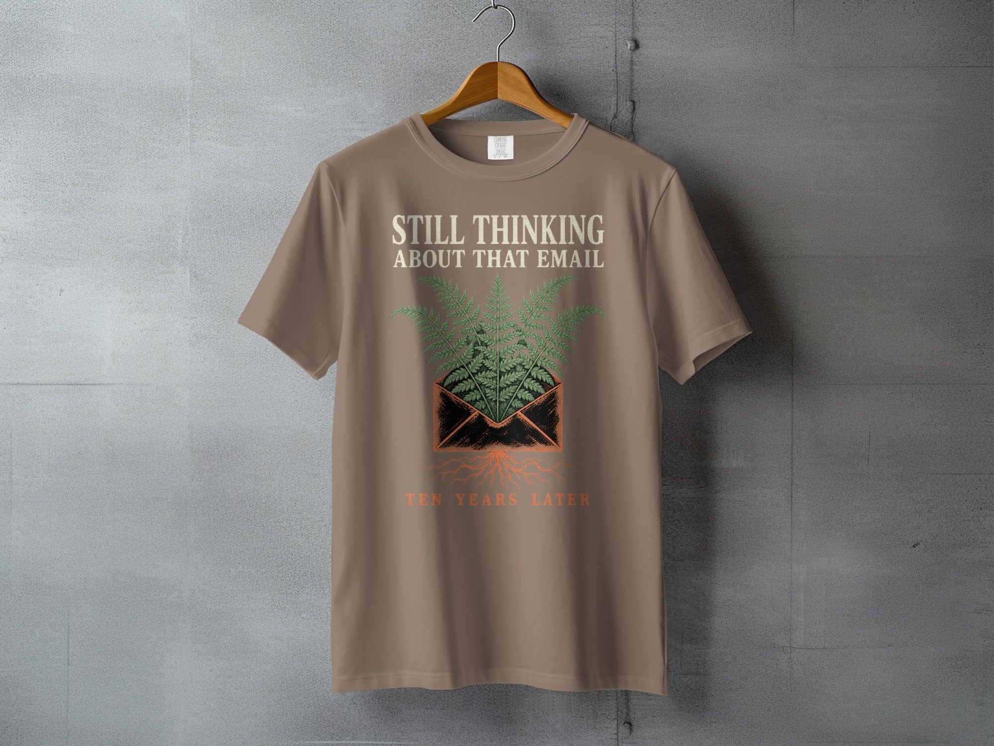 T-shirt with "Still Thinking About That Email Ten Years Later" text and fern design.