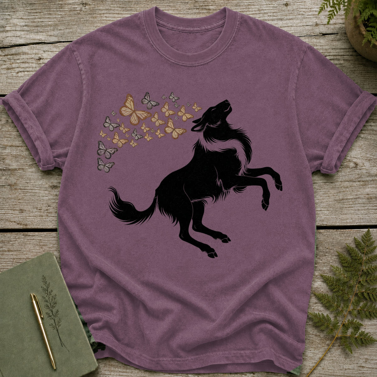 Black wolf silhouette leaping with a swirl of butterflies above it on a purple t-shirt.