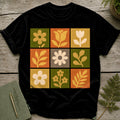 Black t-shirt with nine squares featuring stylized flowers and leaves in muted colors.