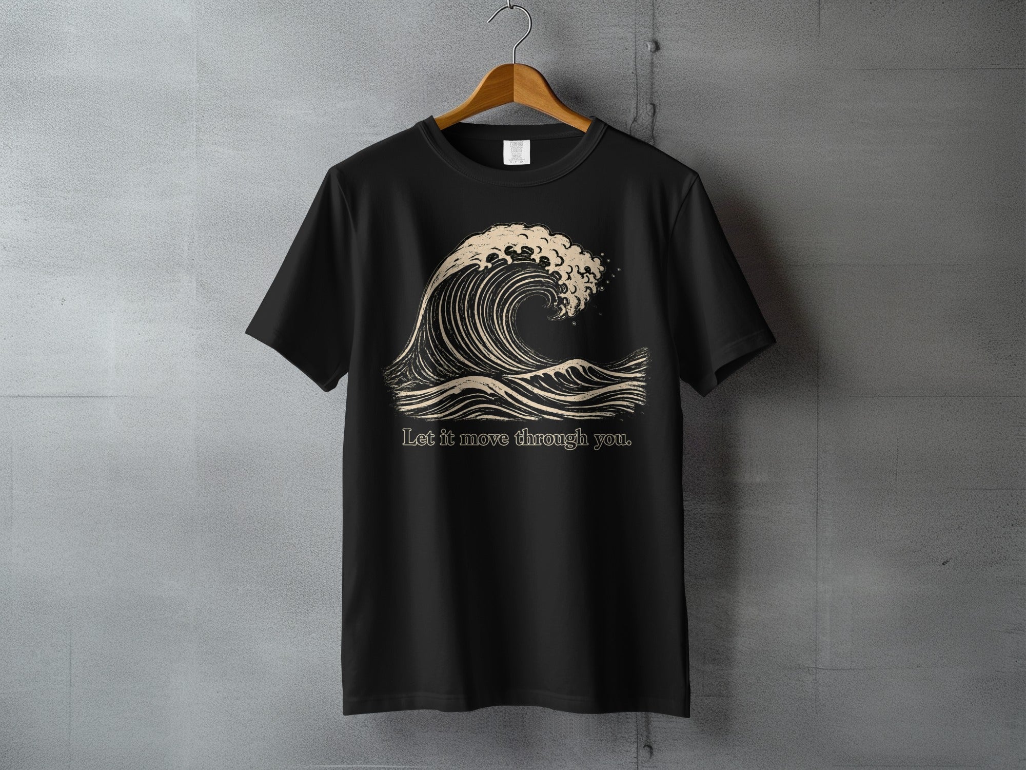 Black t-shirt with a stylized wave graphic and the text "Let it move through you."