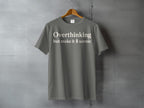 Grey t-shirt with white text "Overthinking but make it scenic" and a pine tree icon.