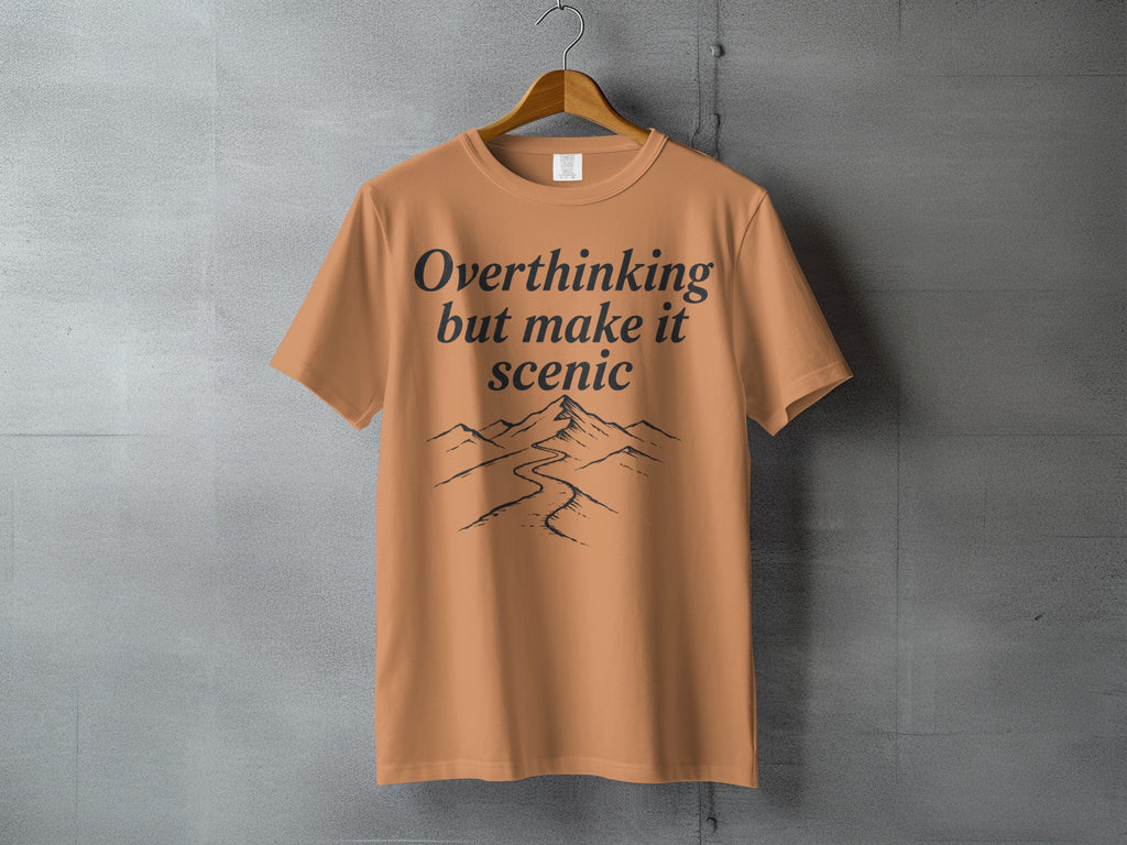 Orange t-shirt with "Overthinking but make it scenic" and mountain graphic.