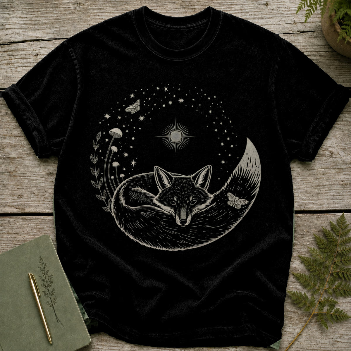 Black t-shirt with a white ink drawing of a sleeping fox surrounded by stars, mushrooms, and moths.