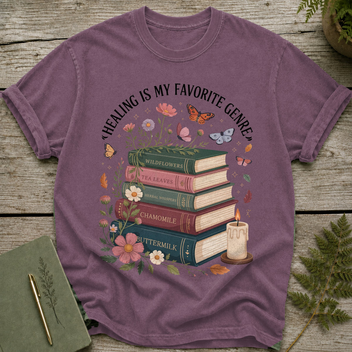 T-shirt with books stacked, "Healing is my favorite genre" text, flowers, butterflies, and candle.