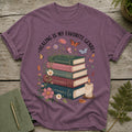 T-shirt with books stacked, "Healing is my favorite genre" text, flowers, butterflies, and candle.