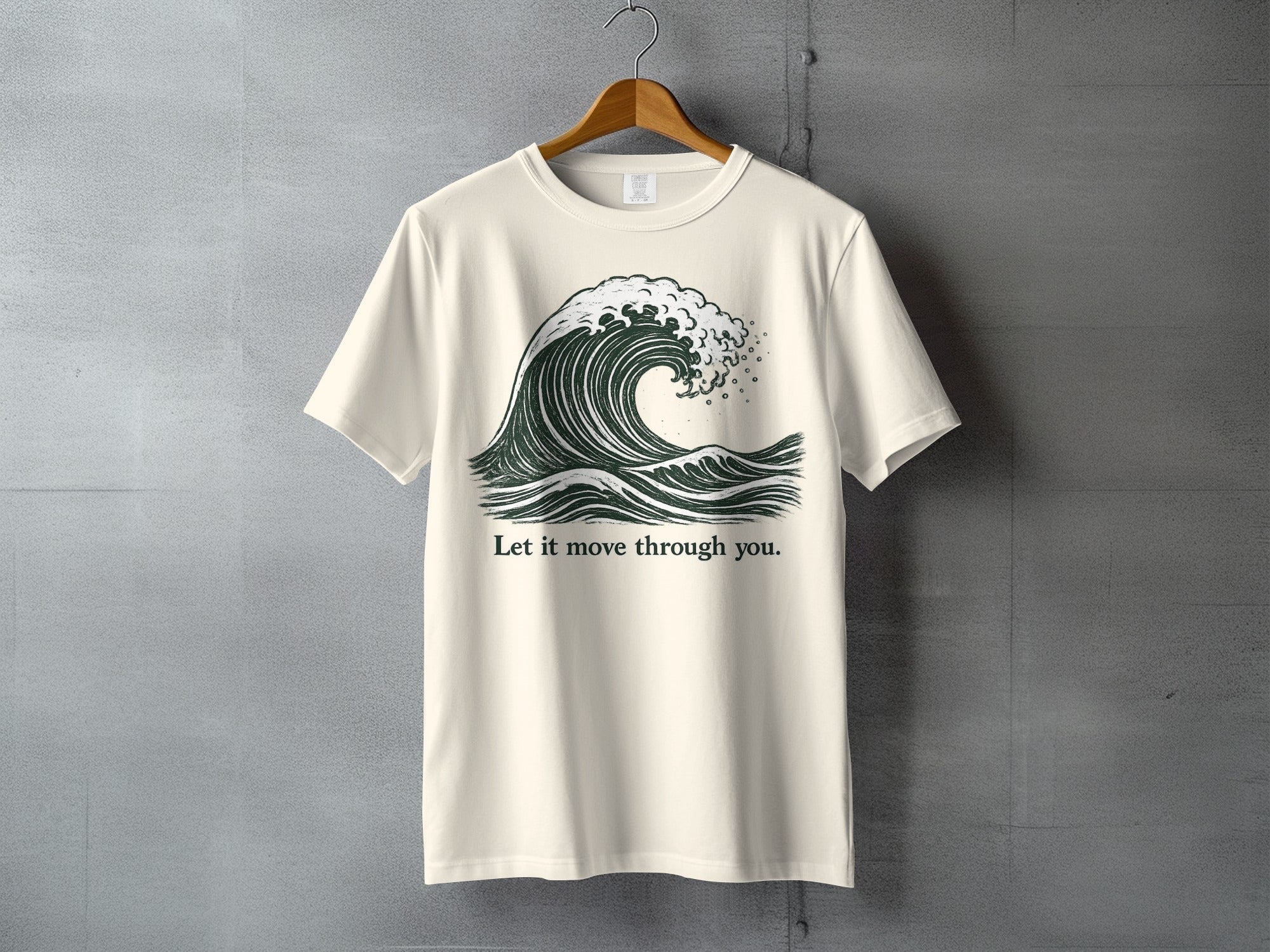 Cream t-shirt with a dark green wave graphic and the text "Let it move through you."