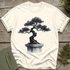 Cream t-shirt with a black ink wash of a twisted bonsai tree in a square pot.