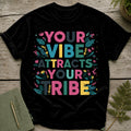 Black t-shirt with colorful text "YOUR VIBE ATTRACTS YOUR TRIBE" and floral accents.