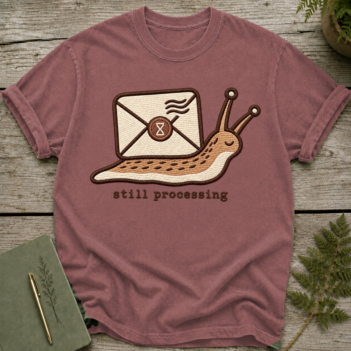 Embroidered t-shirt with snail carrying an envelope and the text "still processing".