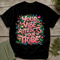 Black t-shirt with "Your Vibe Attracts Your Tribe" text, surrounded by colorful flowers, birds, and butterflies.
