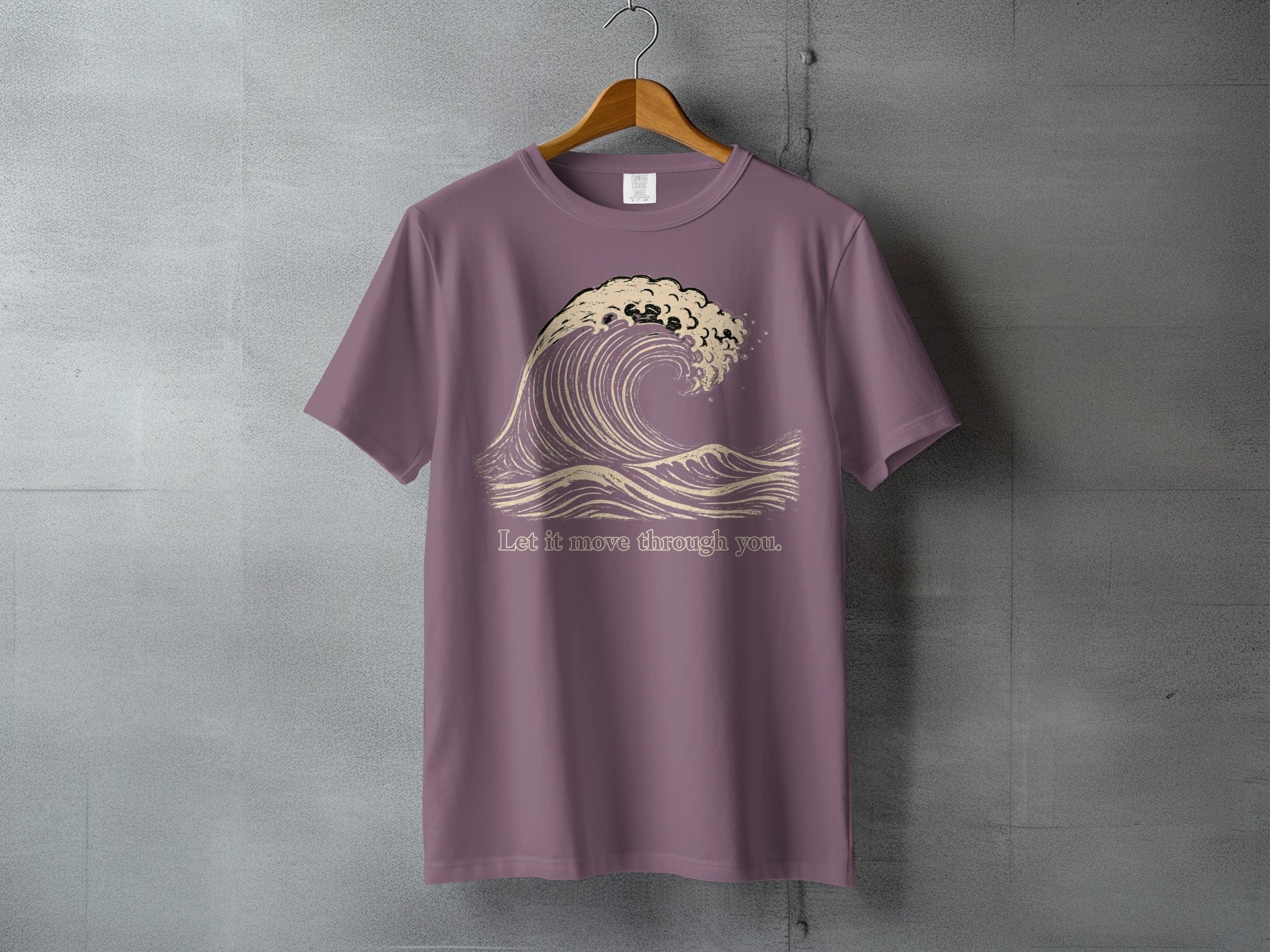 Purple t-shirt with a graphic of a breaking wave and the text "Let it move through you."