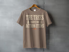 Brown t-shirt with text "THE TREES HAVE NO ACTION ITEMS" and tree graphics.