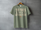Sage green t-shirt with text "THE TREES HAVE NO ACTION ITEMS".