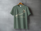 Green t-shirt with a bird on a branch graphic and text "Still here Still moving."