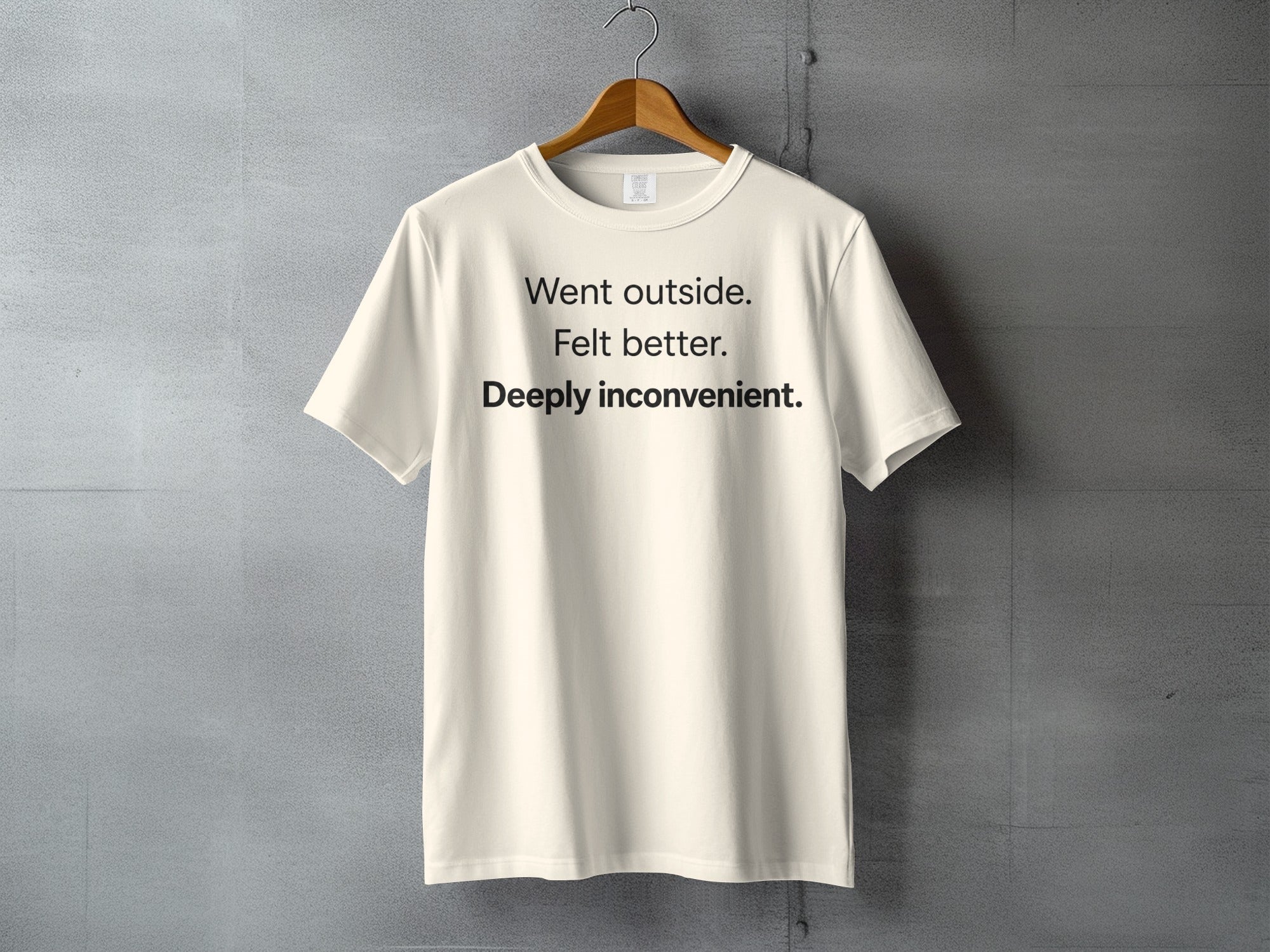 Cream t-shirt with black text reading "Went outside. Felt better. Deeply inconvenient."