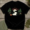 Black t-shirt with forest scene: river, sunrise, trees, flowers, and mug.