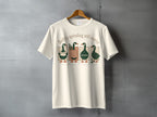 Four cartoon ducks wearing hats on a t-shirt reading "Softly spiraling still moving".