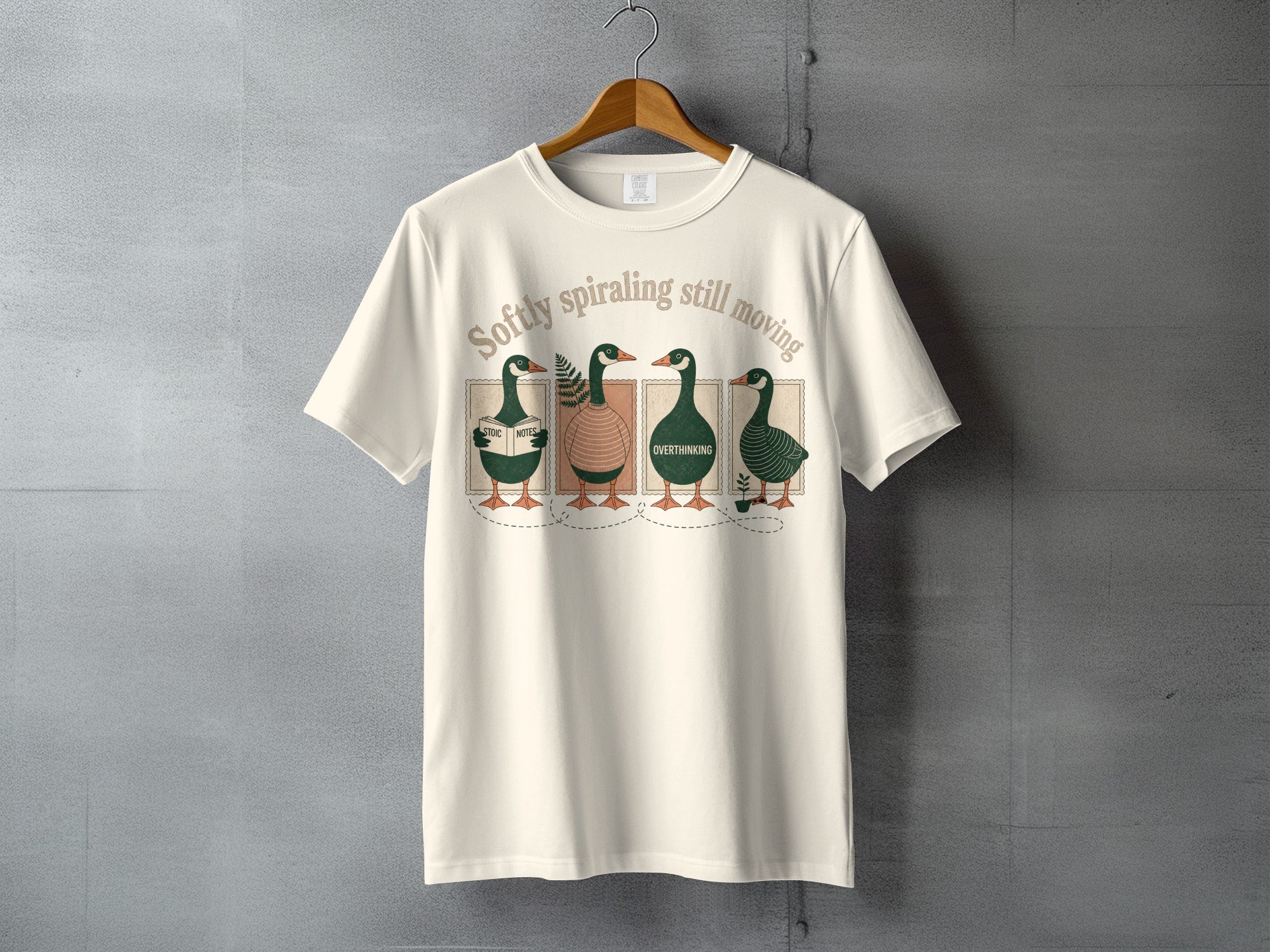 Four cartoon ducks wearing hats on a t-shirt reading "Softly spiraling still moving".