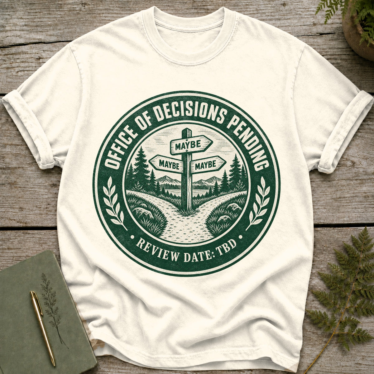Cream t-shirt with "Office of Decisions Pending Review Date: TBD" text and a signpost.