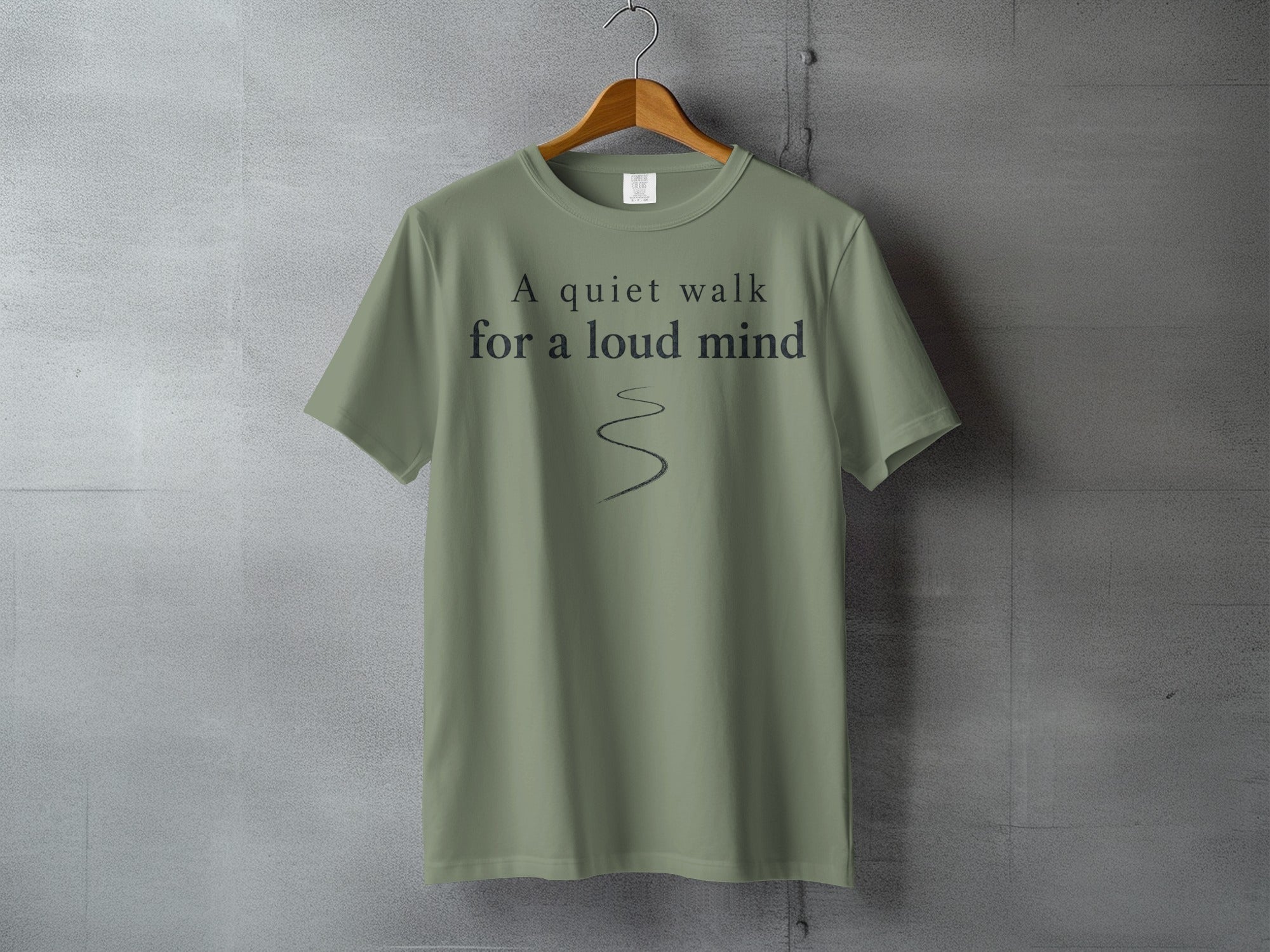 Olive green t-shirt with "A quiet walk for a loud mind" text and a curved line.