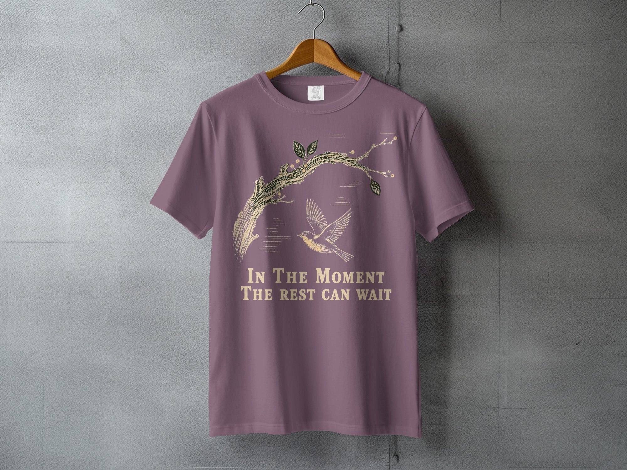 T-shirt with bird and branch graphic, text "In the moment the rest can wait."
