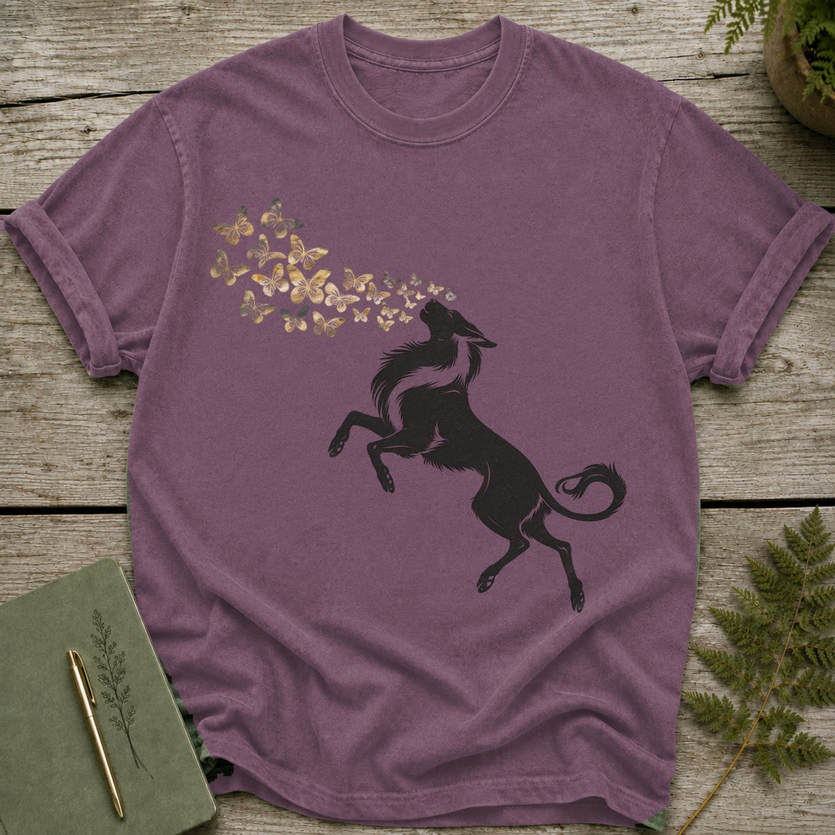 Purple t-shirt with a black wolf silhouette exhaling golden butterflies.