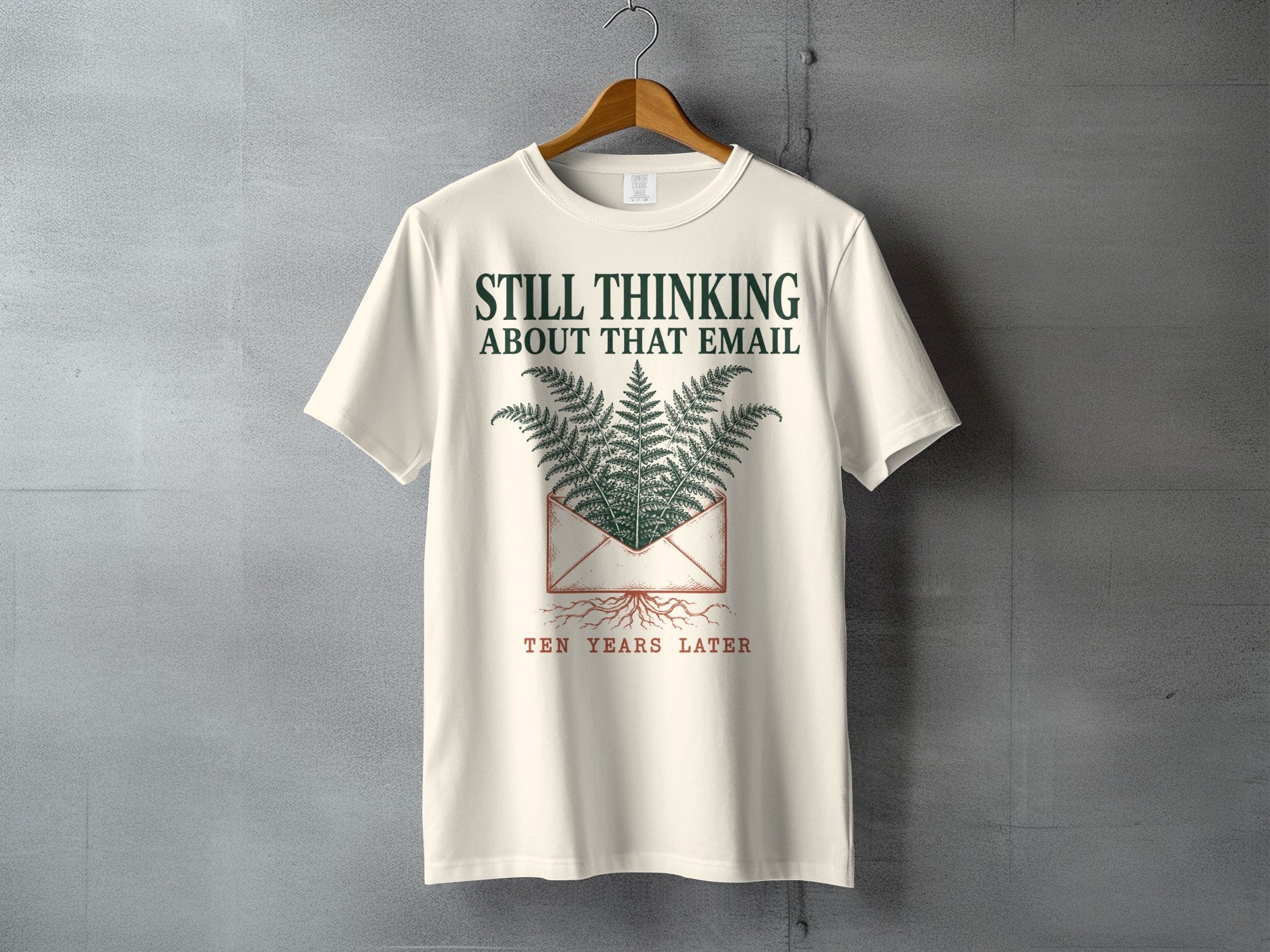 Cream t-shirt with "STILL THINKING ABOUT THAT EMAIL TEN YEARS LATER" and fern graphic.