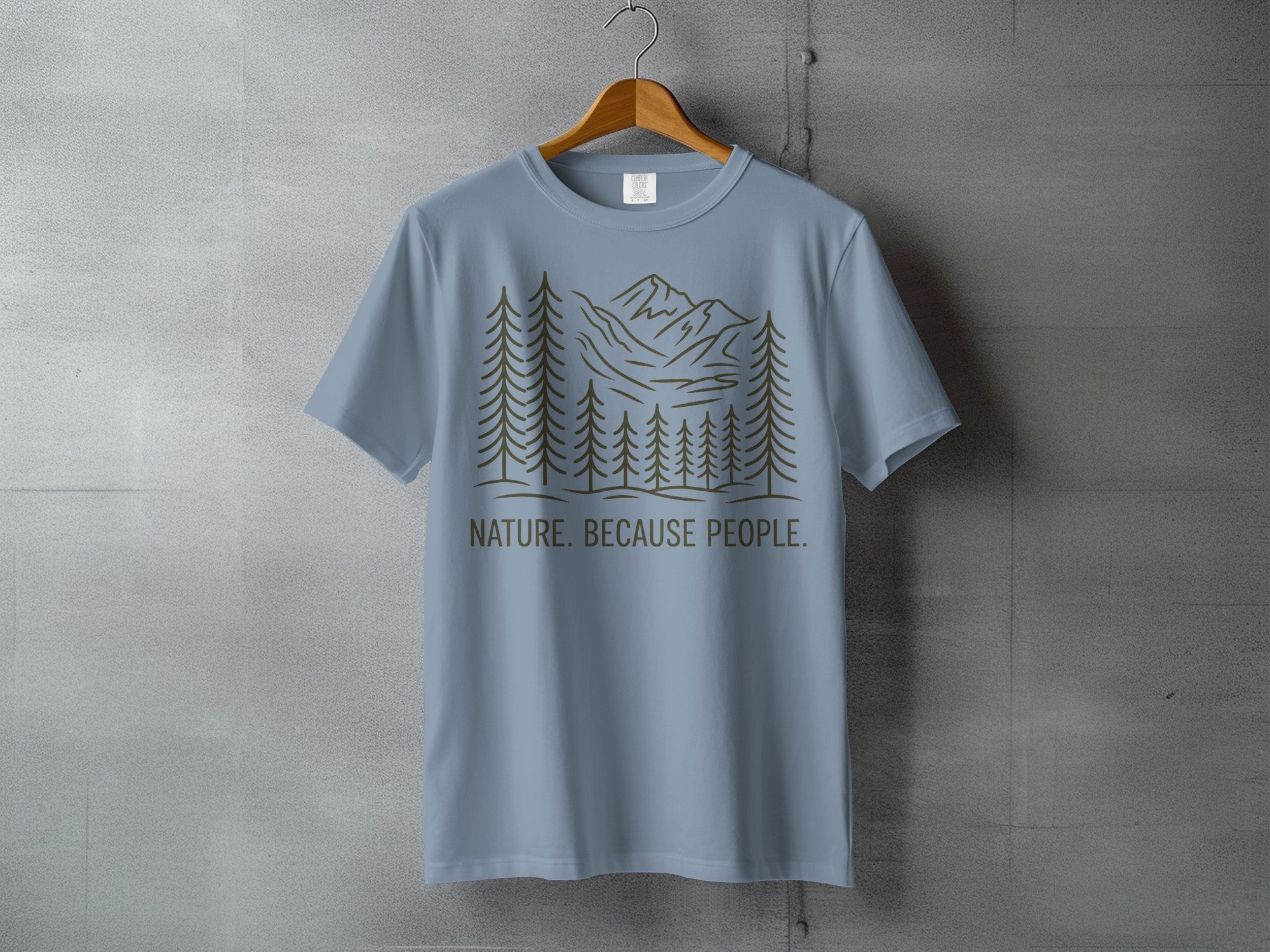 Light blue t-shirt with a minimalist mountain and forest graphic and text.