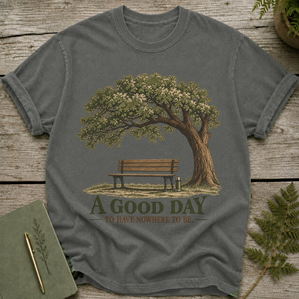 T-shirt with graphic of a tree, bench, and thermos, reads "A GOOD DAY TO HAVE NOWHERE TO BE."