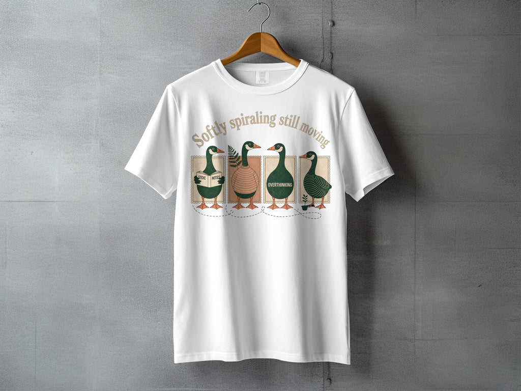 White t-shirt with four ducks reading books and the text "Softly spiraling still moving."