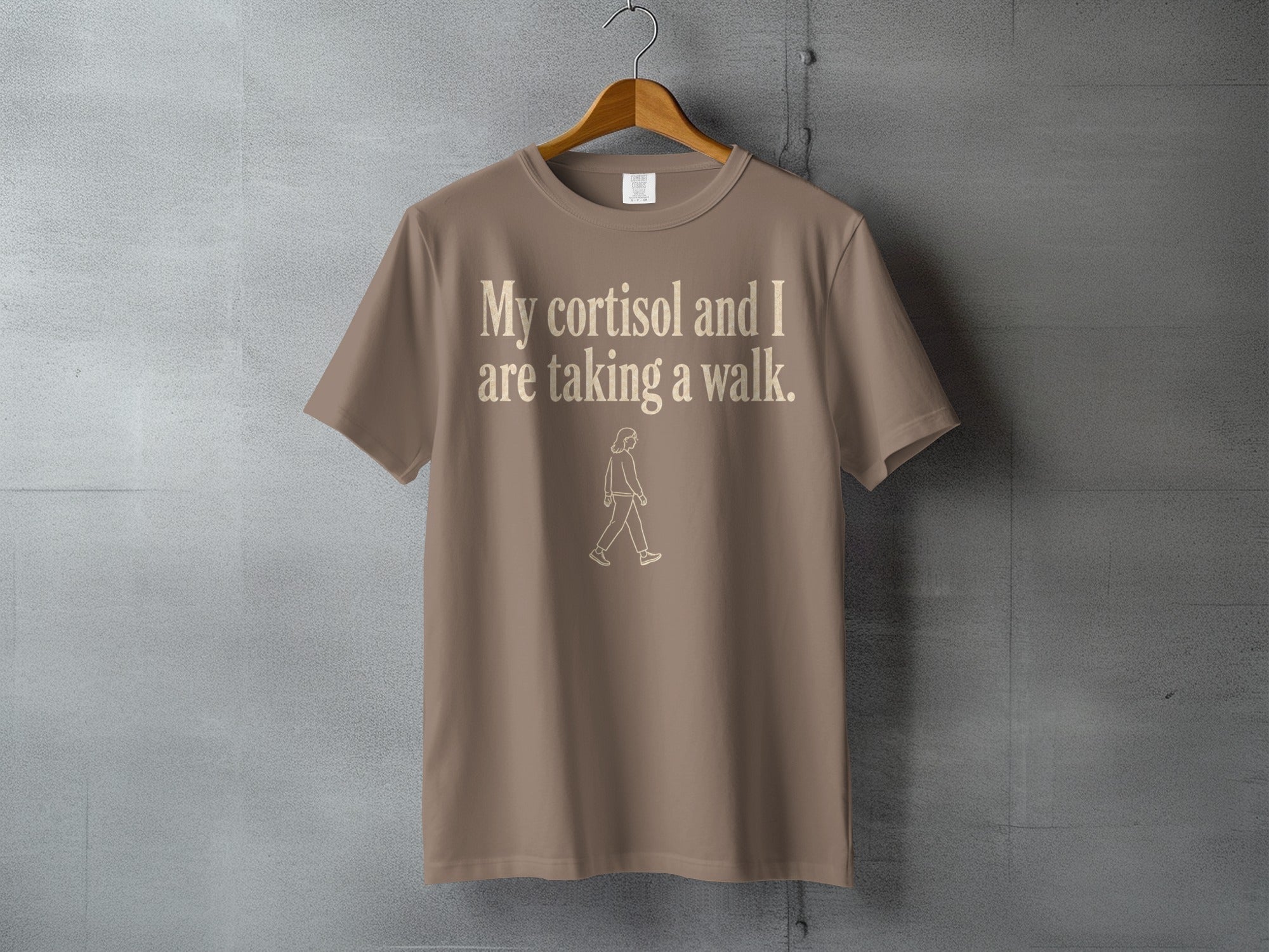 Tan t-shirt with "My cortisol and I are taking a walk" text and walking figure.
