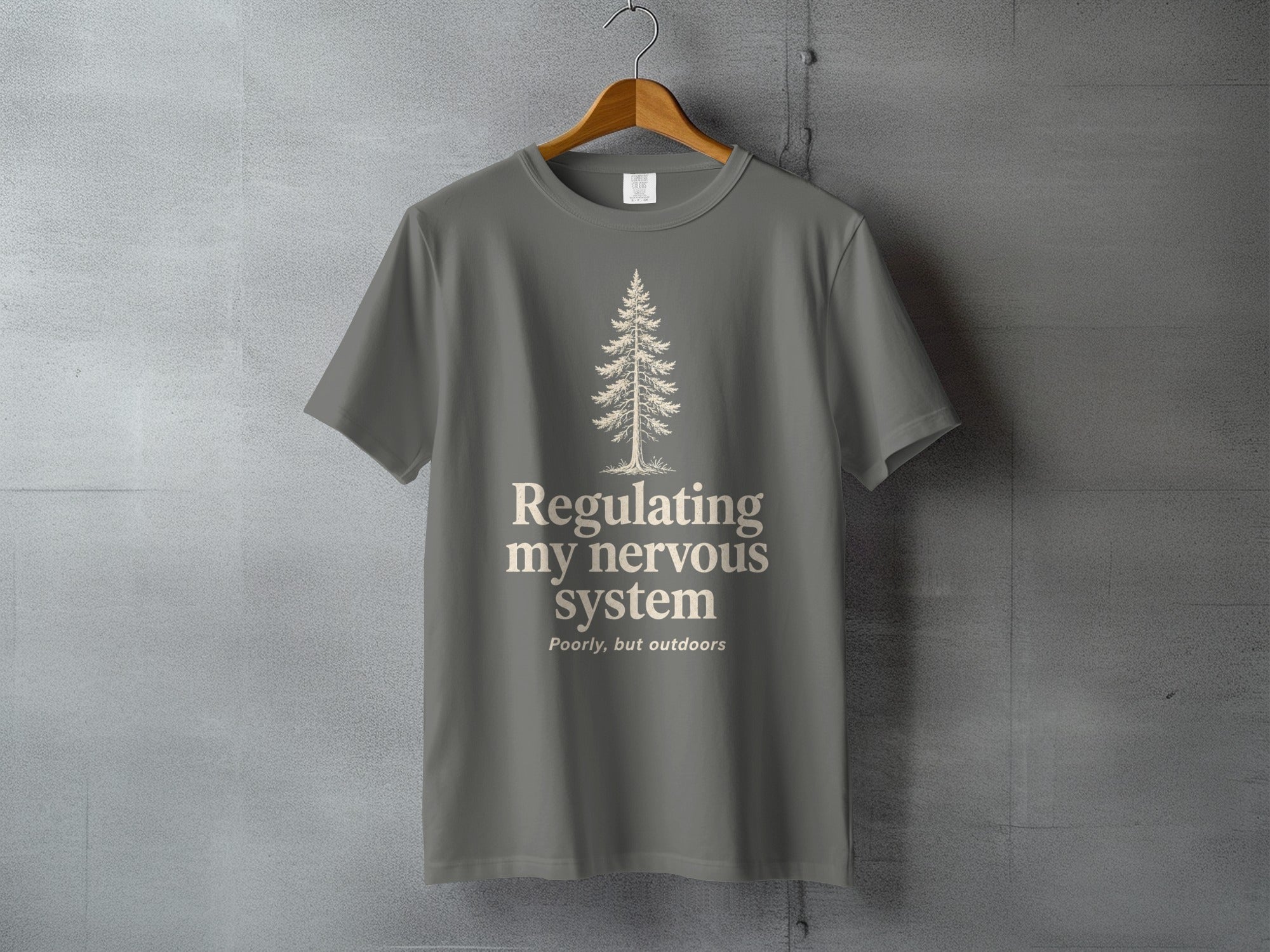 Gray t-shirt with a pine tree and text "Regulating my nervous system Poorly, but outdoors."