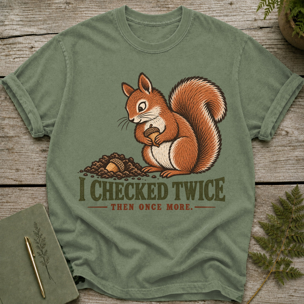 Olive green t-shirt with a squirrel holding an acorn and the text "I checked twice, then once more."
