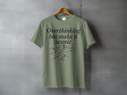 T-shirt with "Overthinking but make it scenic" text and mountain landscape graphic.