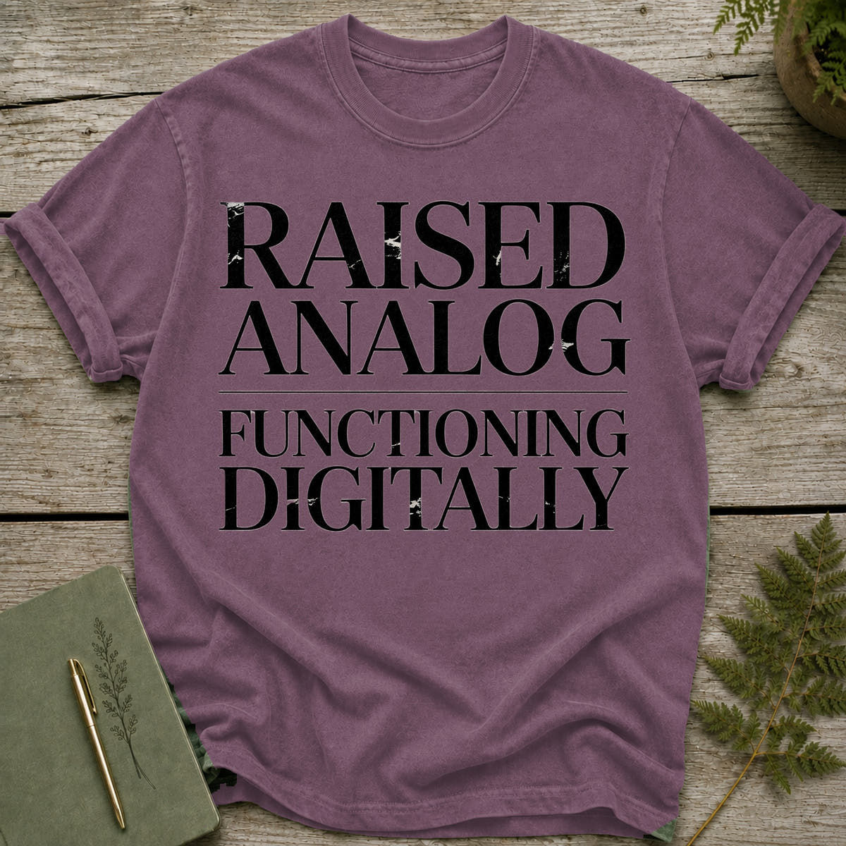 Raised Analog Functioning Digitally text on a purple t-shirt.