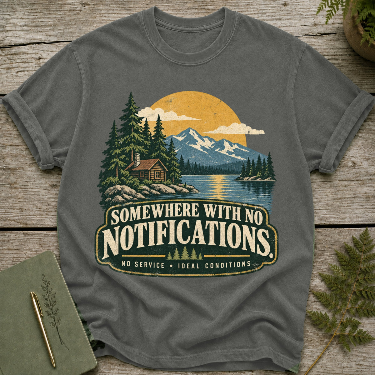 T-shirt with graphic of cabin by lake with mountains and text "SOMEWHERE WITH NO NOTIFICATIONS".