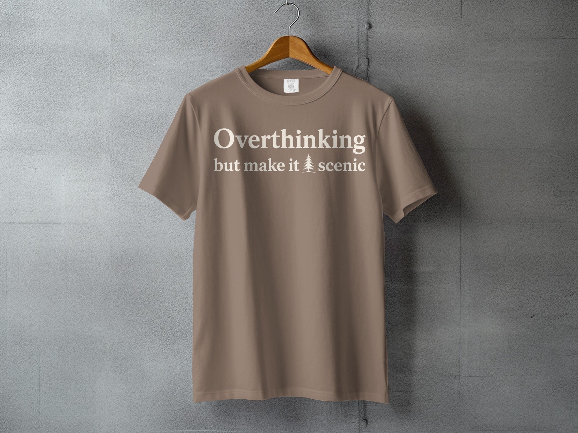 Taupe t-shirt with white text "Overthinking but make it 🌲 scenic"
