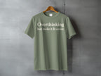 Olive t-shirt with "Overthinking but make it scenic" text and a tree graphic.