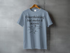 Blue t-shirt with "Overthinking but make it scenic" text and mountain graphic.