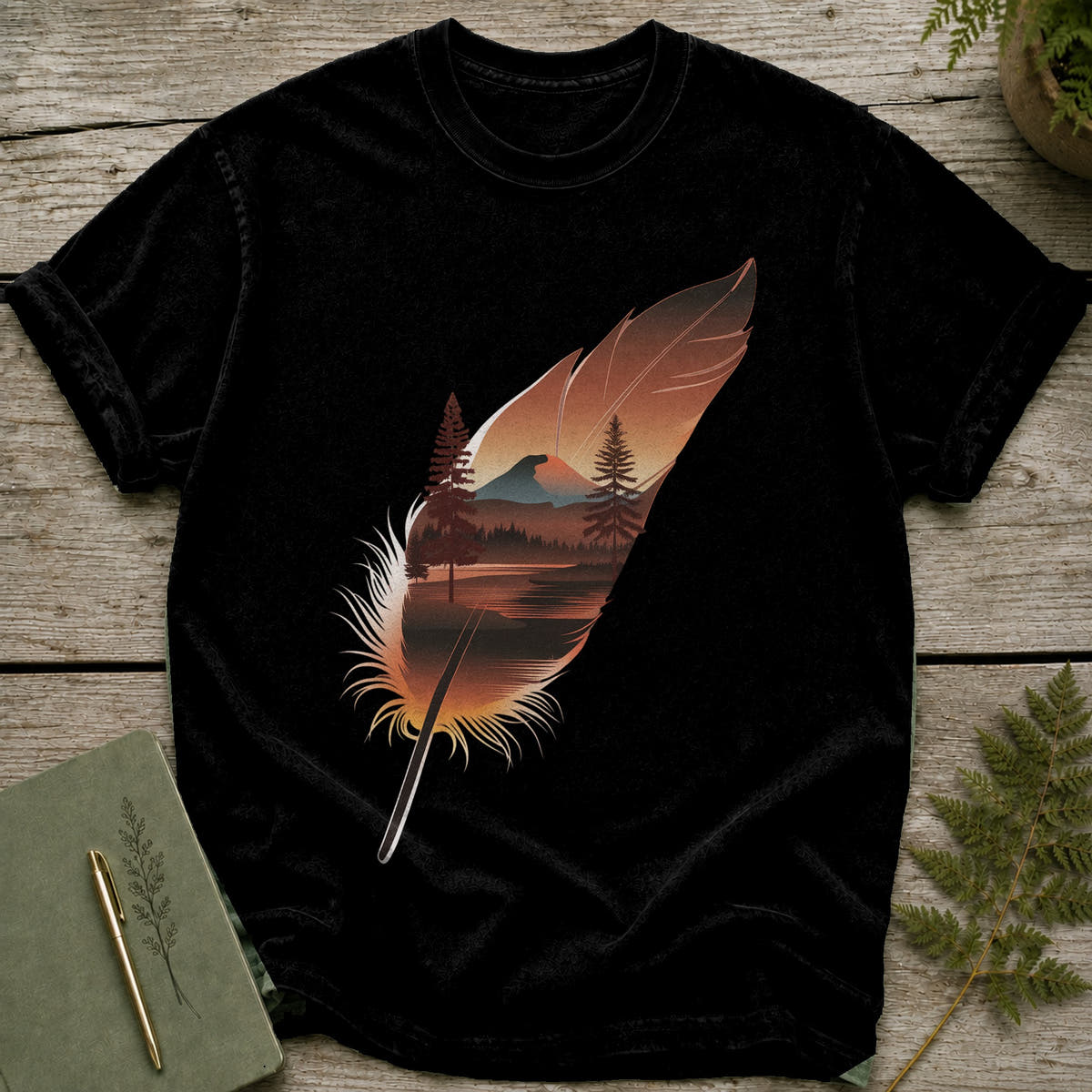 Black t-shirt with a feather graphic depicting a forest and mountain landscape.