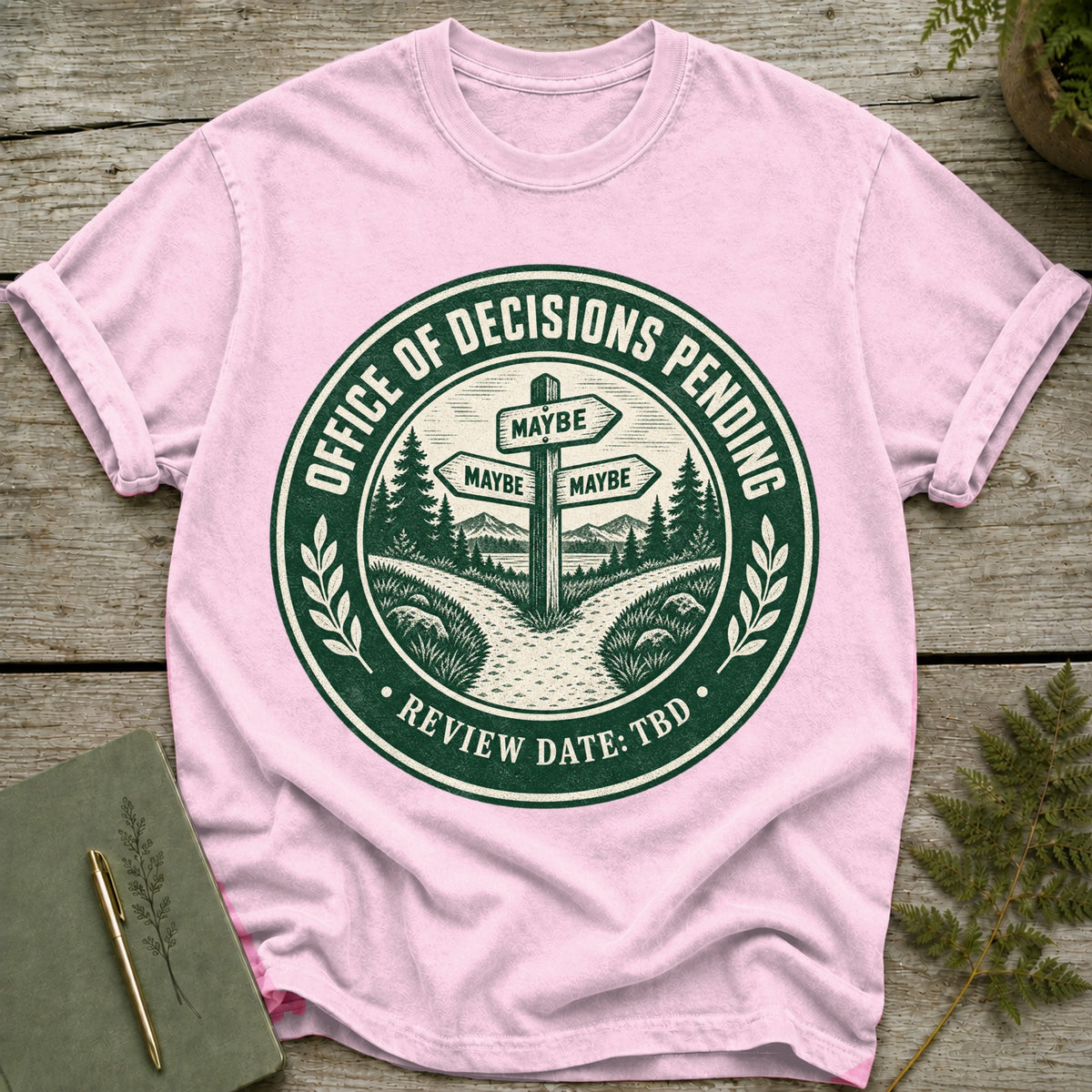 Pink t-shirt with a green circular graphic: "Office of Decisions Pending" and "Review Date: TBD".