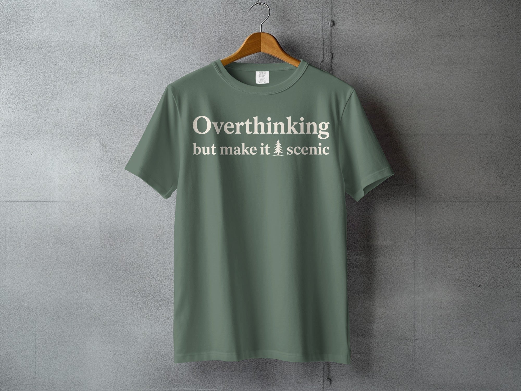 Green t-shirt with cream text "Overthinking but make it 🌲 scenic"