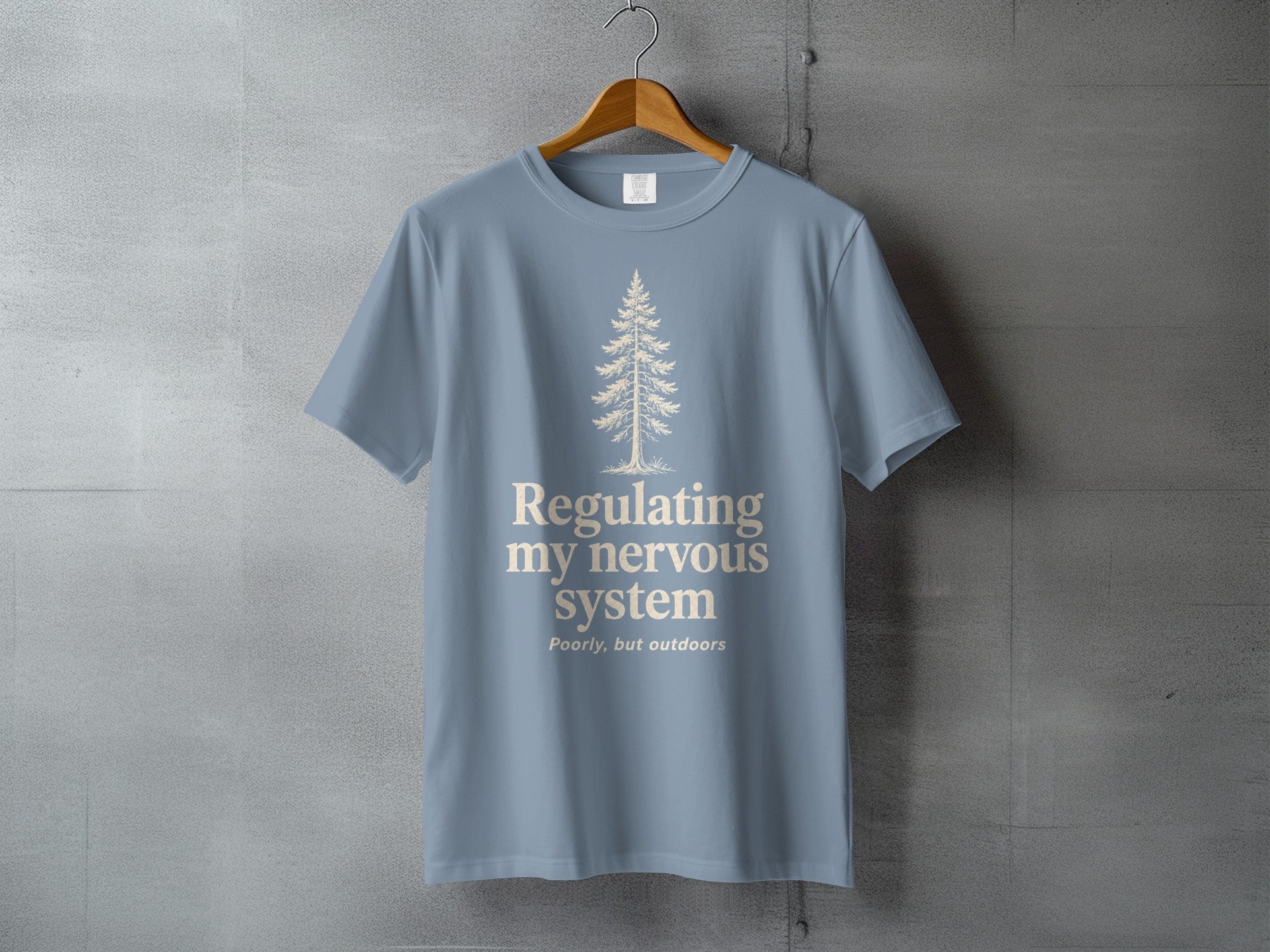 Blue t-shirt with tree and text "Regulating my nervous system Poorly, but outdoors".