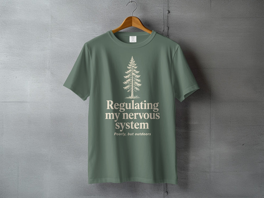 Green t-shirt with a pine tree and text "regulating my nervous system poorly, but outdoors".